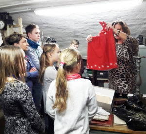 HistoryKids im Depot des Kreismuseums: Leiterin Manuela Vehme zeigt den Kindern das aus Fahnenstoff genähte Kleid und erzählt die Geschichte dazu. (Foto: Ulrike Unger)