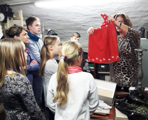 HistoryKids im Depot des Kreismuseums: Leiterin Manuela Vehme zeigt den Kindern das aus Fahnenstoff genähte Kleid und erzählt die Geschichte dazu. (Foto: Ulrike Unger)