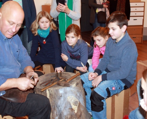 Schmied und Metallkünstler Olaf Hannemann erklärt den Kindern die Technik der Metallbearbeitung (Foto: Babett Wiechmann)