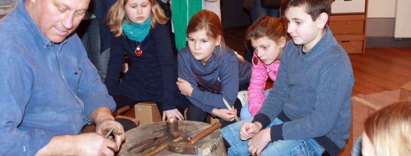 Schmied und Metallkünstler Olaf Hannemann erklärt den Kindern die Technik der Metallbearbeitung (Foto: Babett Wiechmann)